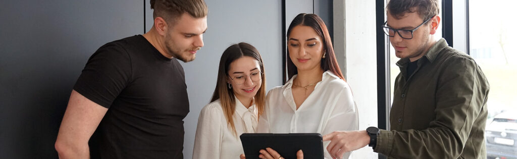 Vier Personen blicken auf Tablet