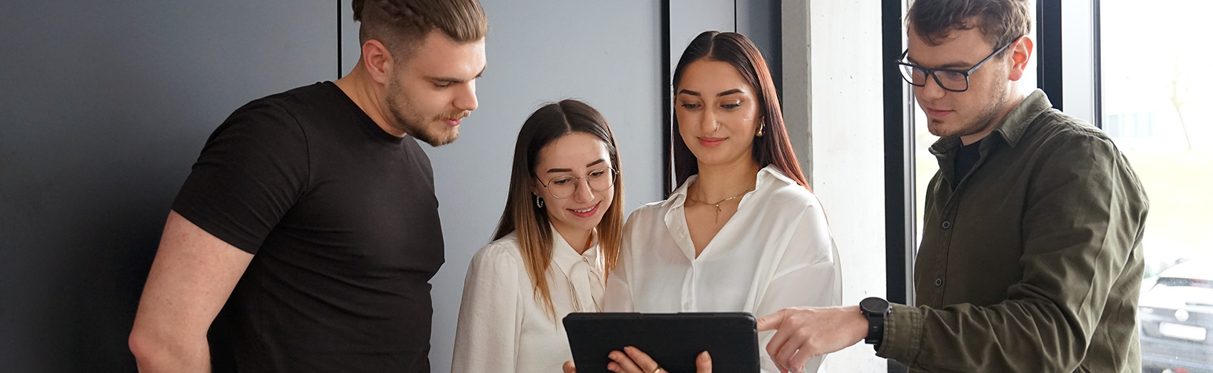 Vier Personen blicken auf Tablet
